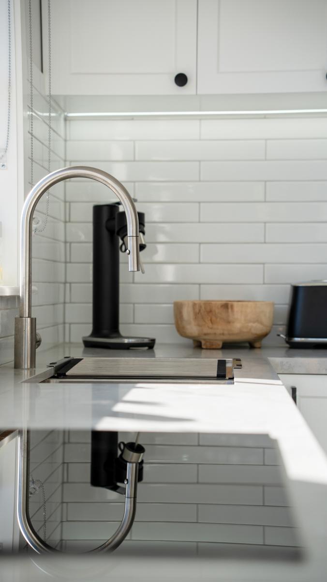 Modern white kitchen with chrome tap, marble countertop and subway tile splashback