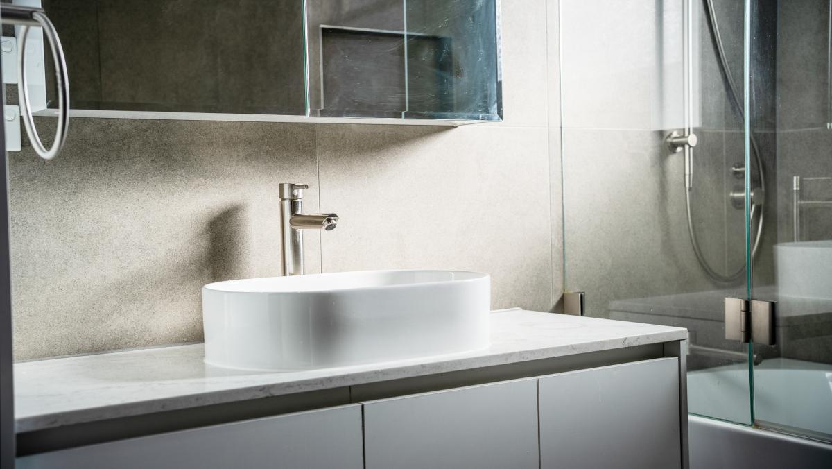 Modern luxury bathroom with white vessel basin, brushed nickel tap, and glass shower screen