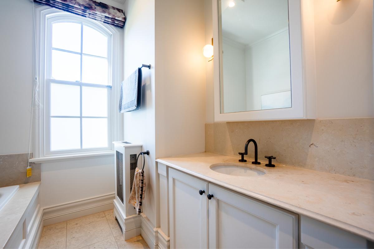 Elegant white bathroom renovation with marble benchtop, traditional window, and modern black tapware fixtures
