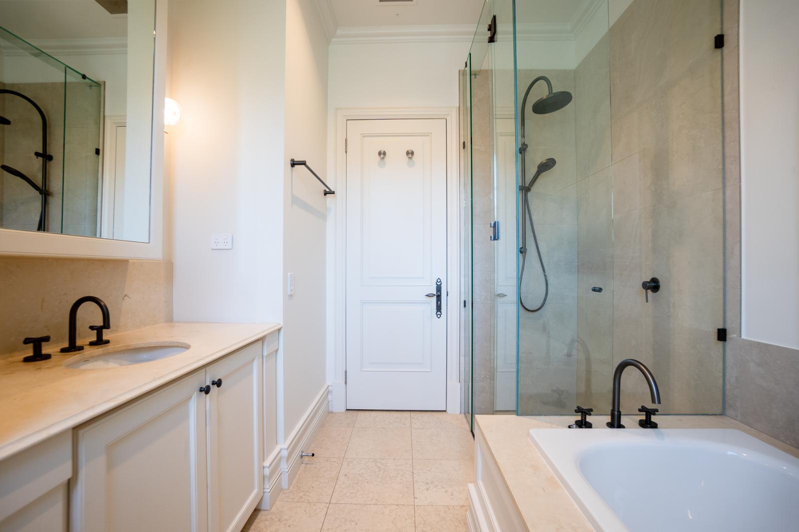 Luxury bathroom renovation with white vanity, black taps, glass shower and modern finishes in Melbourne home