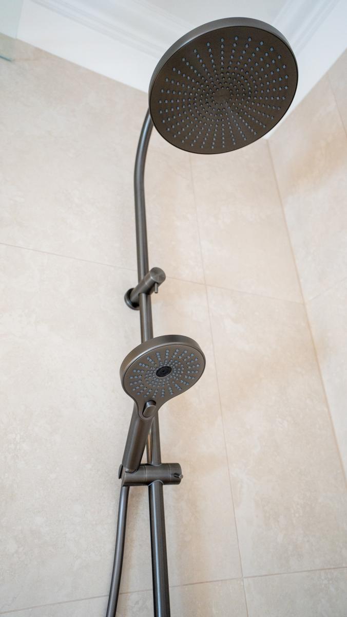 Modern brushed nickel dual shower system with rainfall head and handheld unit in luxury bathroom