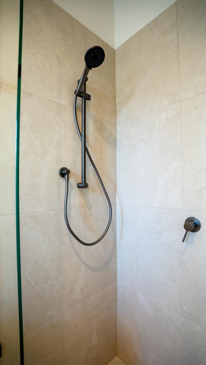 Modern luxury bathroom shower with black fixtures, marble-effect tiles and glass screen
