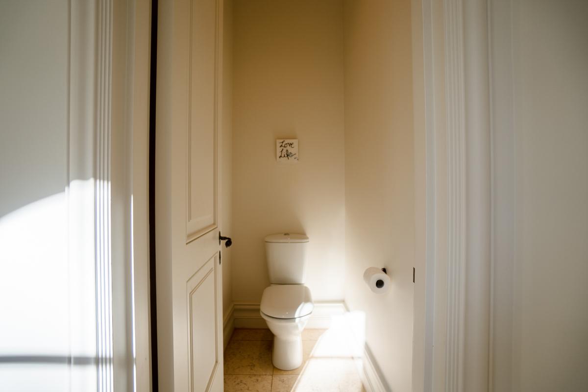 Modern powder room with white toilet, marble tiles, and natural light through glass doors