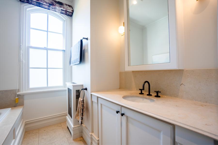 Elegant bathroom renovation featuring white vanity with natural stone benchtop and black tapware