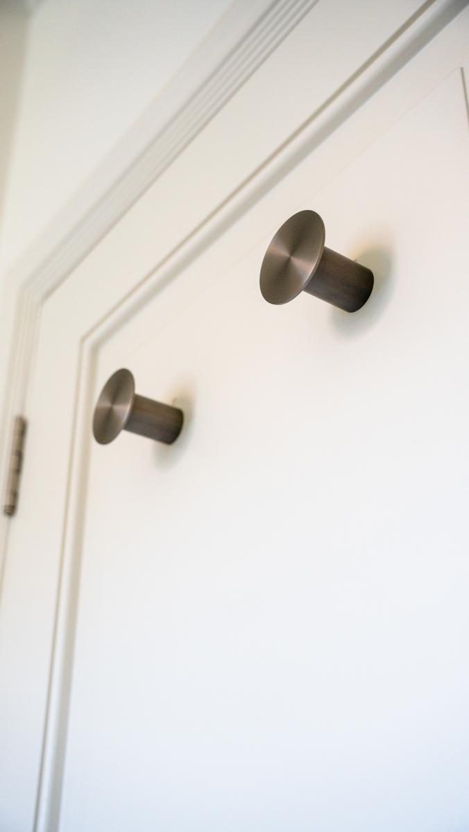 Modern bronze cabinet knobs on white kitchen cabinetry with detailed panel moulding