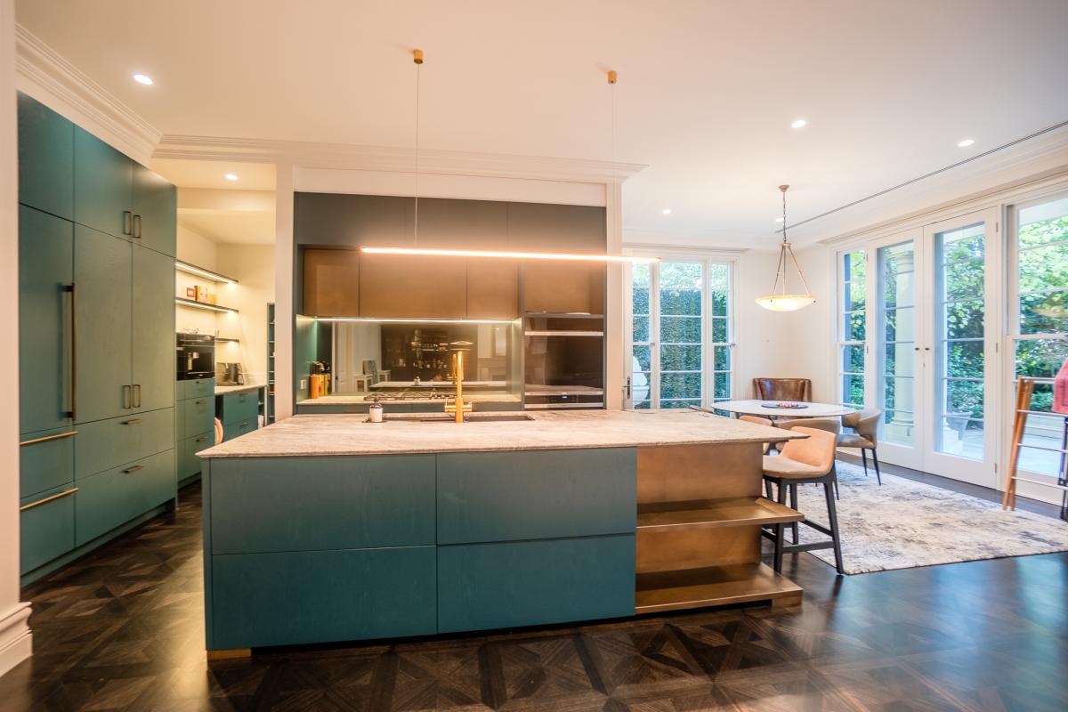 Modern luxury kitchen with teal cabinetry, marble island bench and integrated dining area