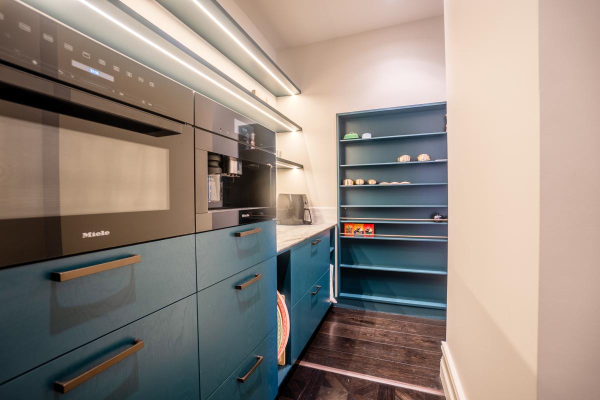 Modern luxury kitchen pantry with blue cabinetry, Miele appliances, and integrated LED strip lighting