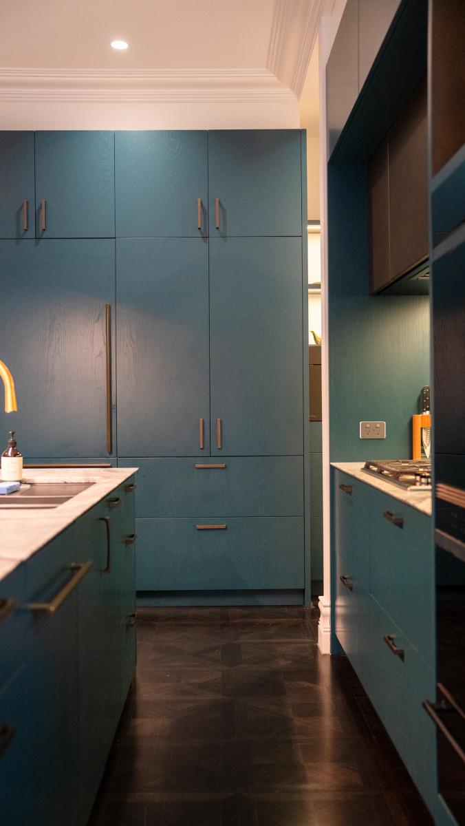 Modern luxury kitchen with sage green cabinetry, brass handles, marble benchtops and integrated appliances