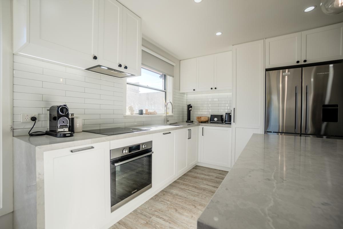Modern white kitchen with marble benchtops, subway tile splashback and stainless steel appliances