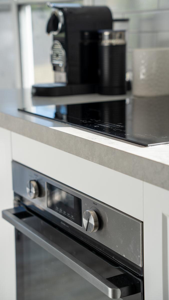 Modern luxury kitchen featuring built-in stainless steel microwave and coffee machine with stone benchtop