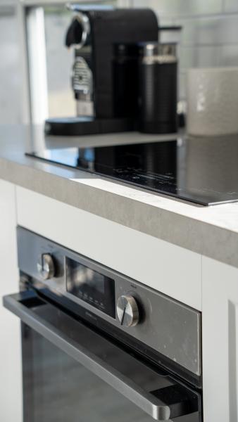 Modern luxury kitchen featuring built-in stainless steel microwave and coffee machine with stone benchtop